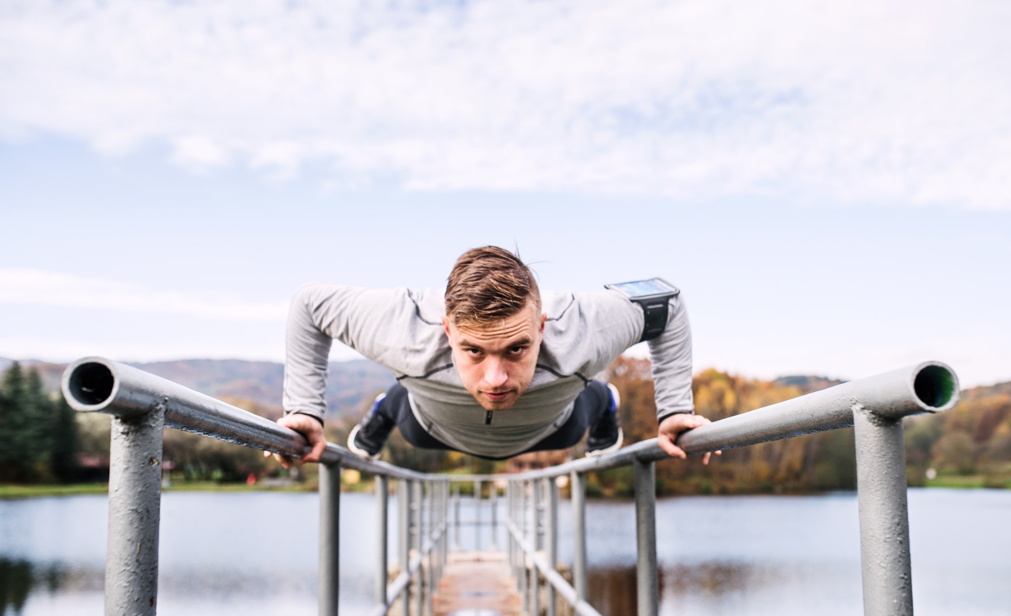 Young man with smartphone doing exercise in park.